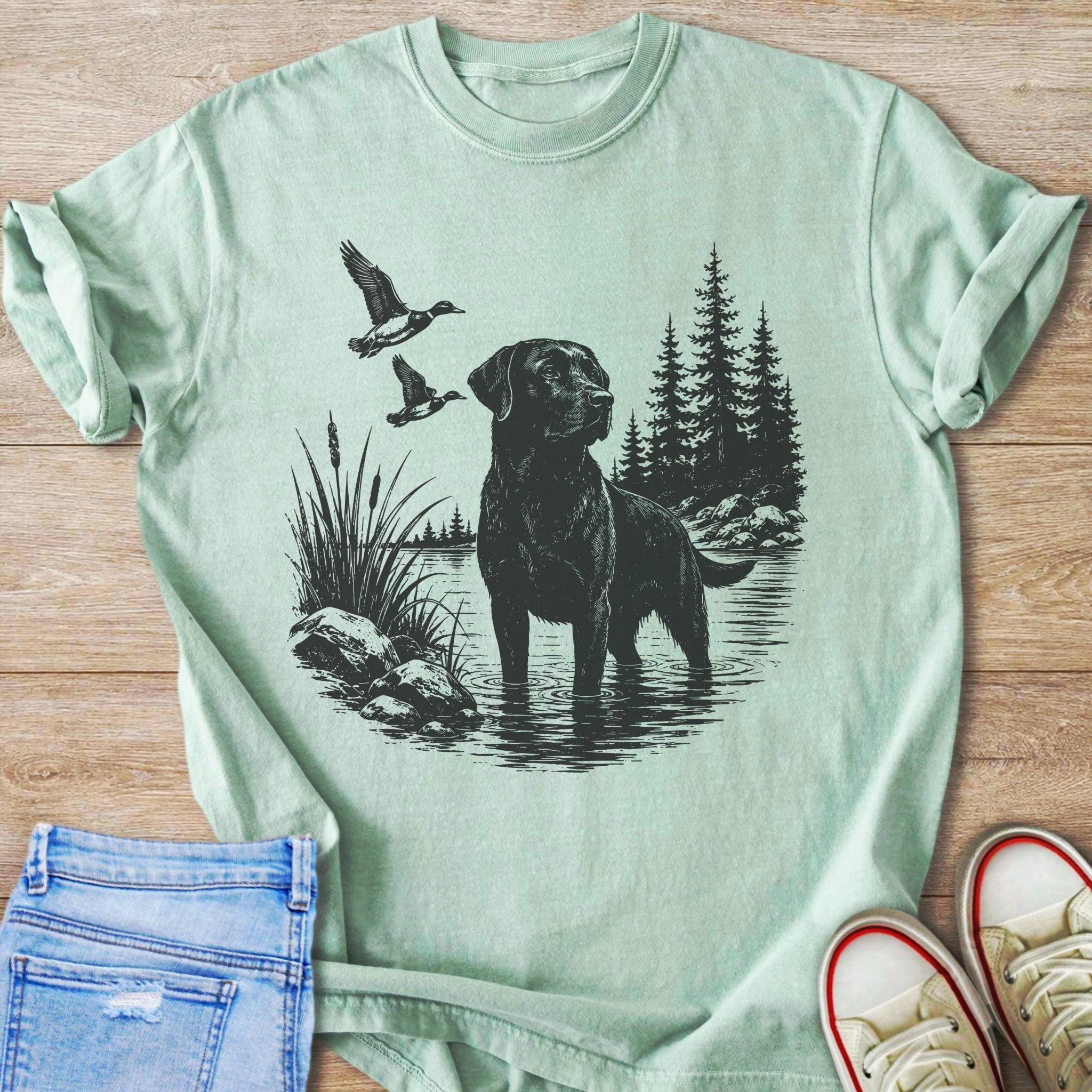 Black Labrador wading in water with ducks flying over reeds by trees