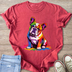 French bulldog with rainbow-colored fur sitting on a pink shirt with distressed jeans and shoes.