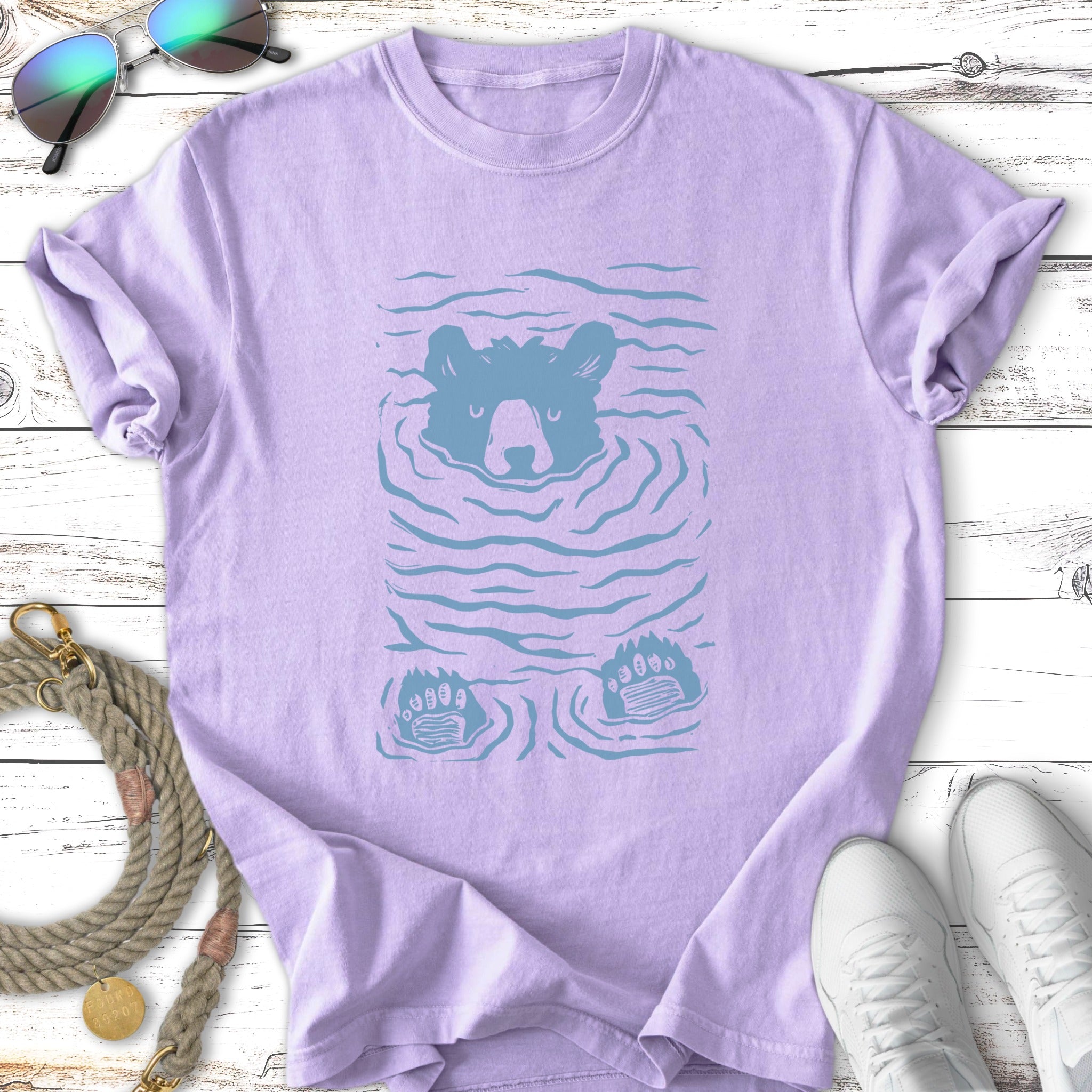 Lavender t-shirt with a blue graphic of a bear's face and paws submerged in water.