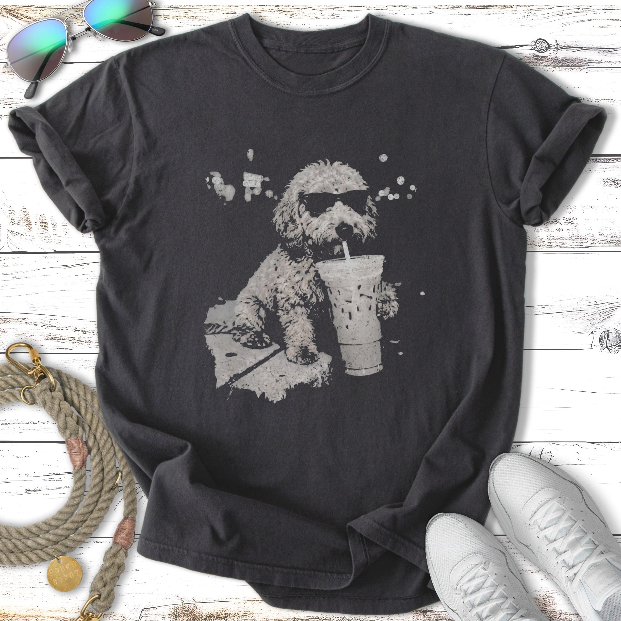 T-shirt graphic of a poodle wearing sunglasses drinking from a large cup.