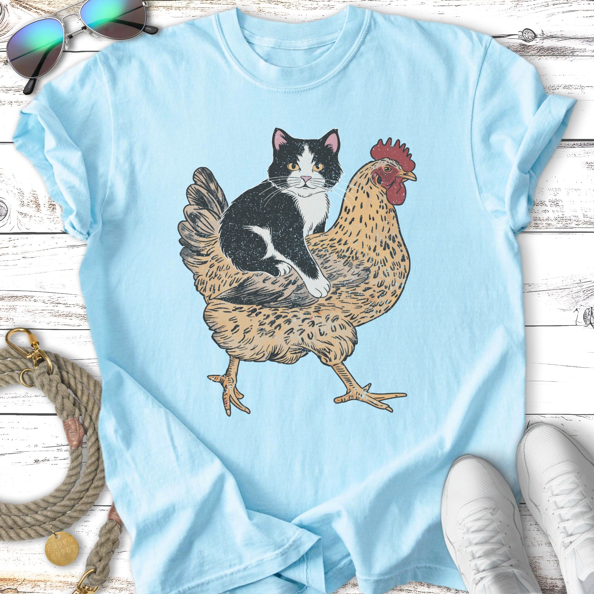 T-shirt graphic of a black and white cat riding a chicken.