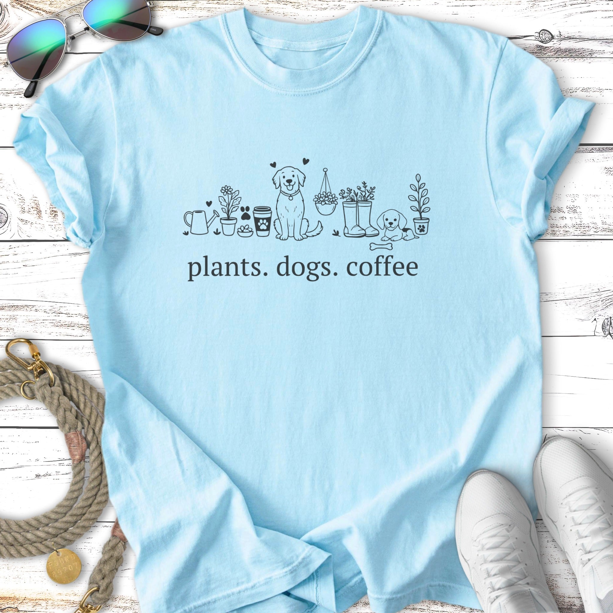 Light blue t-shirt with "plants. dogs. coffee" and line art.