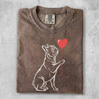 Line art French bulldog holding a red heart balloon, on a brown t-shirt.