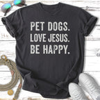 Dark grey t-shirt with white text "PET DOGS. LOVE JESUS. BE HAPPY."
