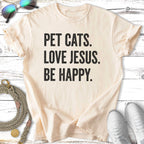 Cream t-shirt with "PET CATS. LOVE JESUS. BE HAPPY." text.