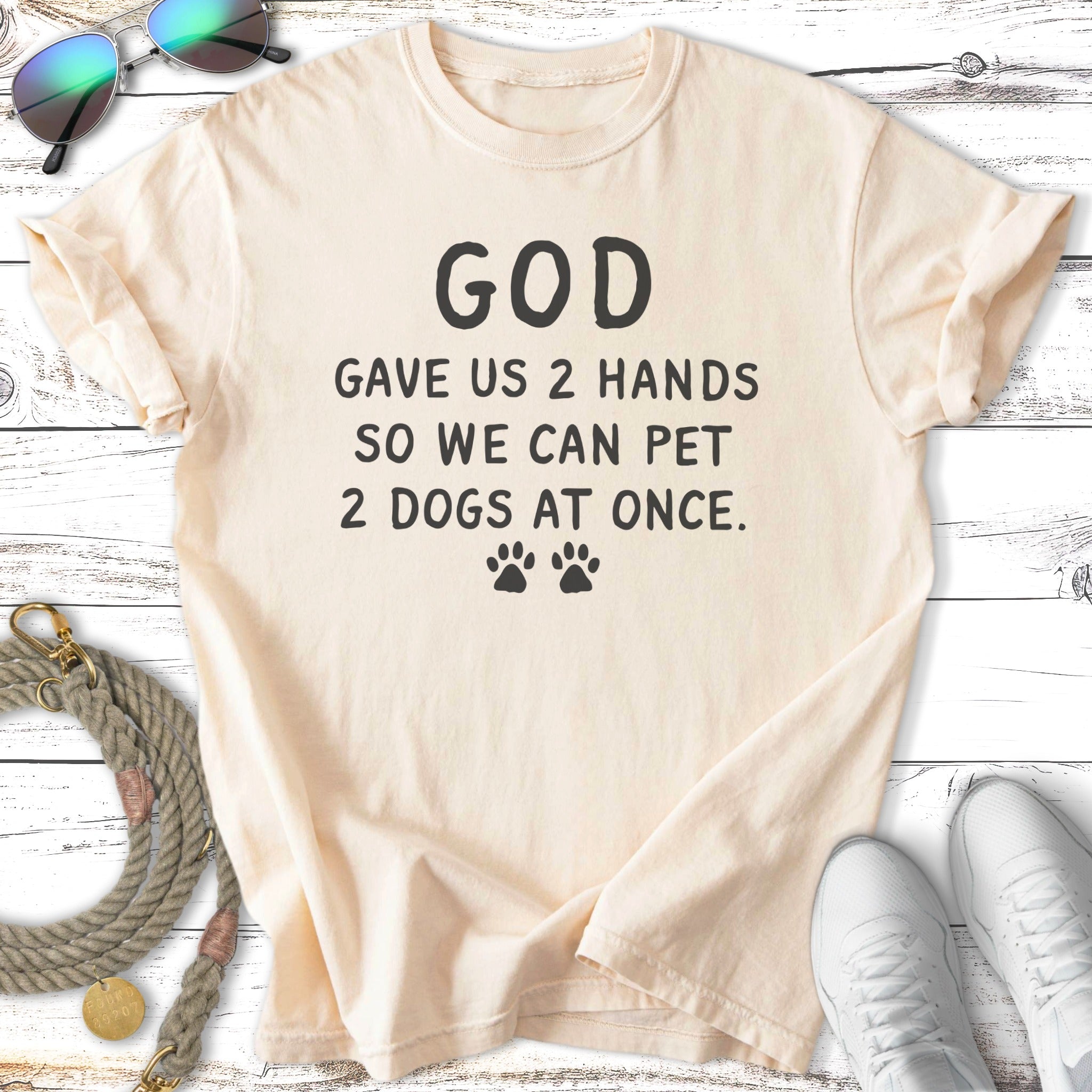 Cream t-shirt with "God gave us 2 hands so we can pet 2 dogs at once" text and paw prints.