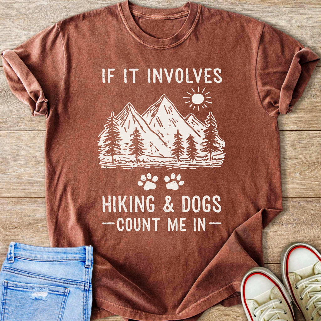 Brown t-shirt with mountains, trees, sun, and text "If it involves hiking & dogs - count me in -"