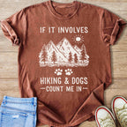 Brown t-shirt with mountains, trees, sun, and text "If it involves hiking & dogs - count me in -"