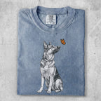 German Shepherd dog sitting, looking at a butterfly on its nose.