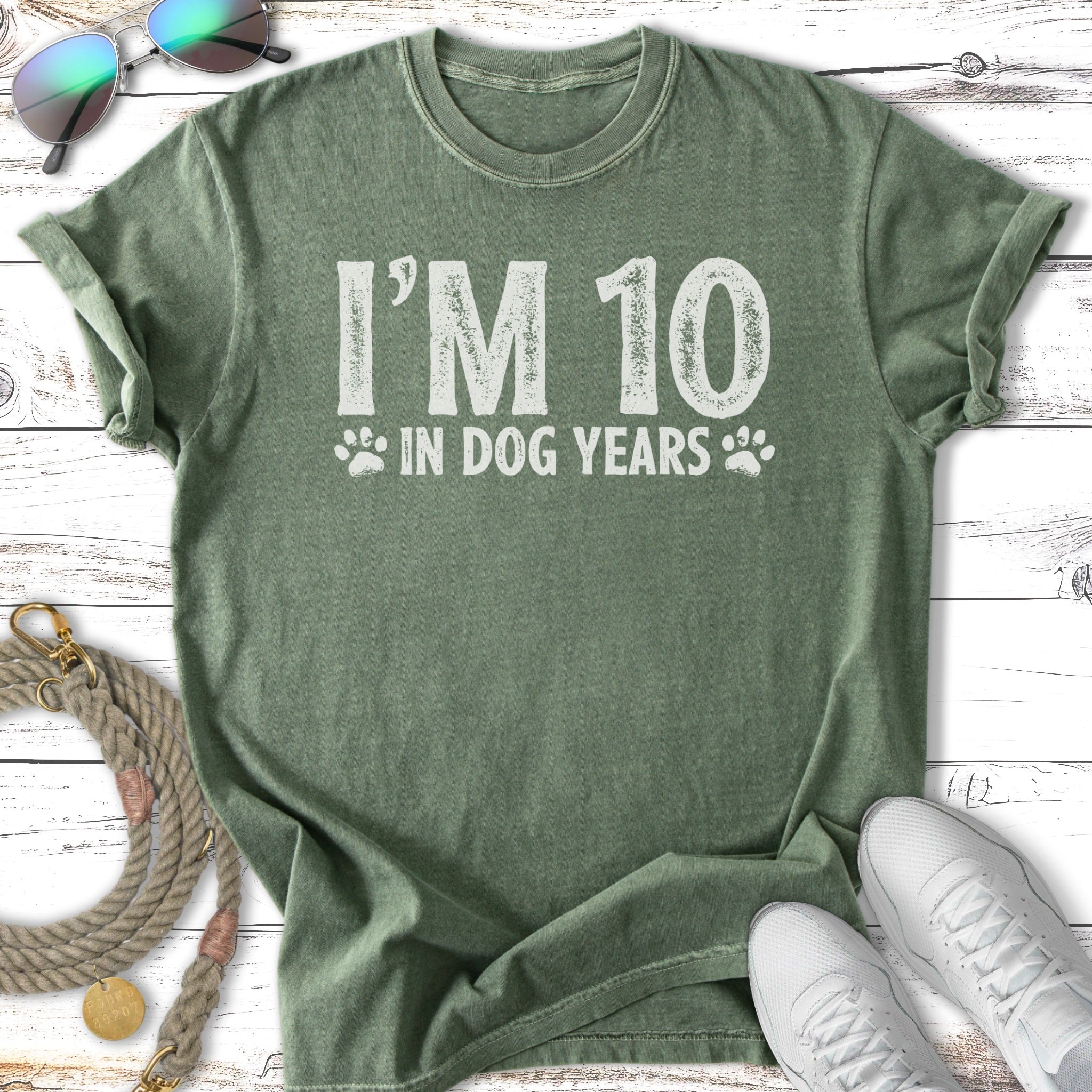 Green t-shirt with "I'M 10 IN DOG YEARS" text and paw prints.