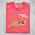 T-shirt with dachshund in hot dog costume lounging under umbrella with sunscreen.