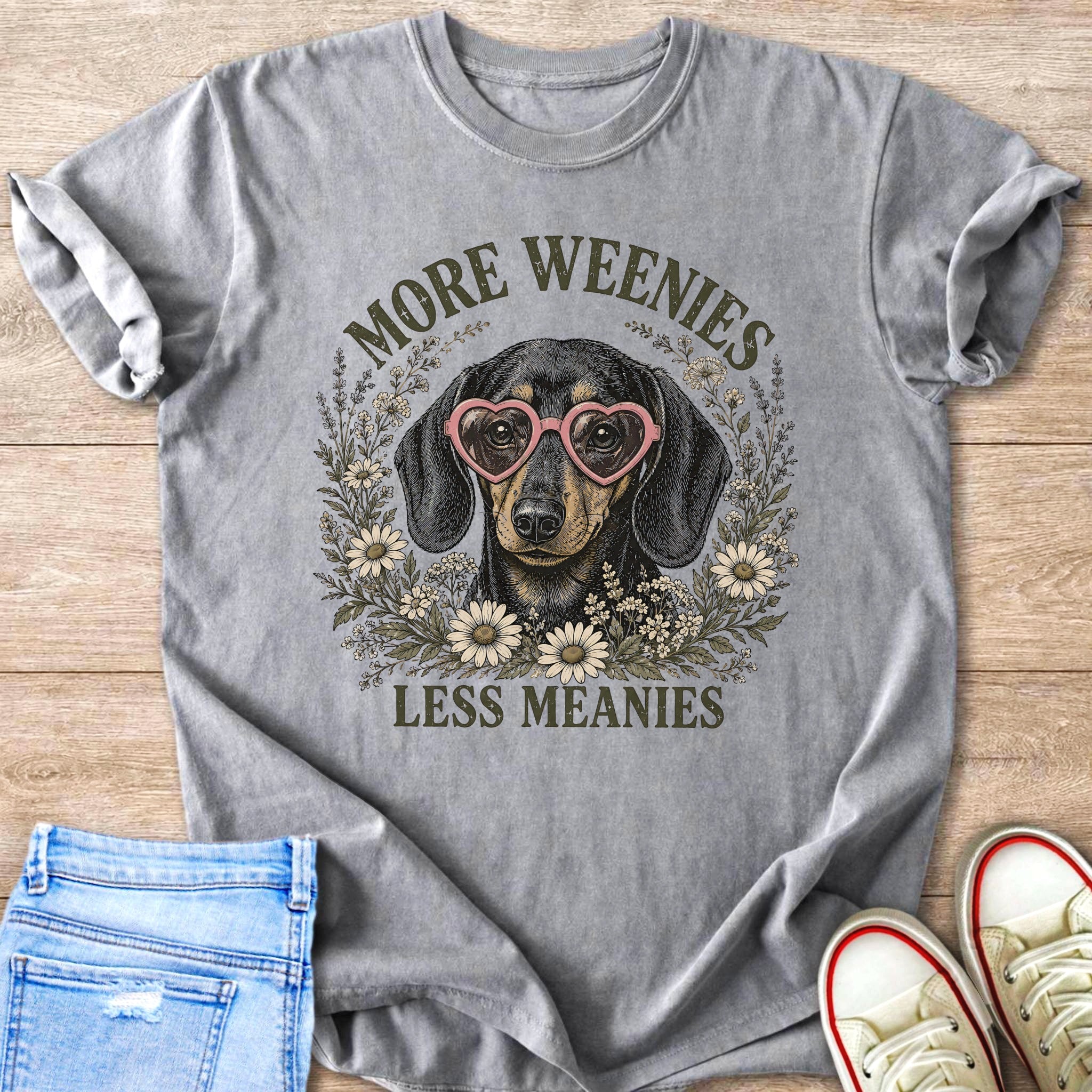 Dachshund wearing heart glasses surrounded by flowers with text "More Weenies Less Meanies".