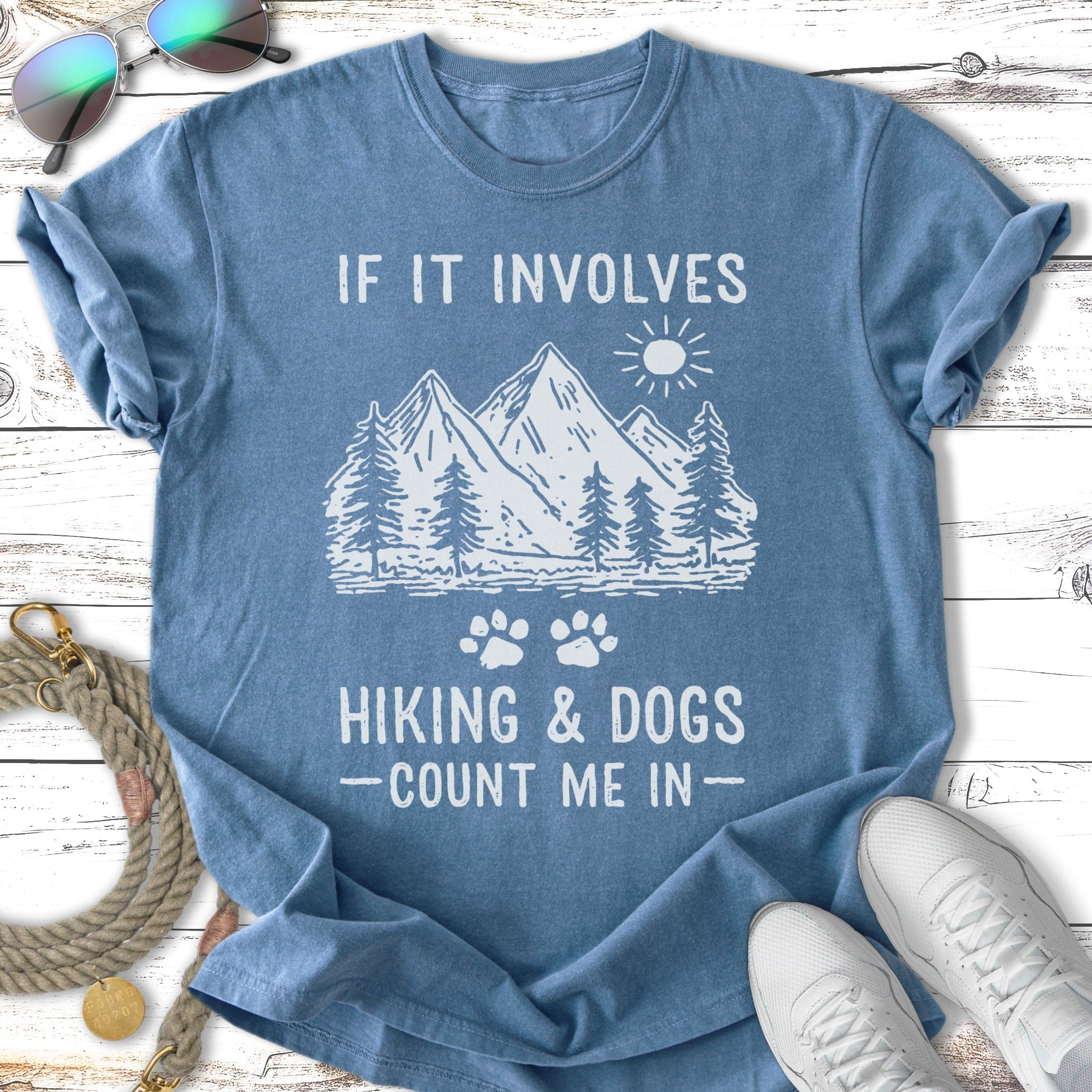 Blue t-shirt with mountain, tree, and paw print graphic and text "IF IT INVOLVES HIKING & DOGS - COUNT ME IN -".