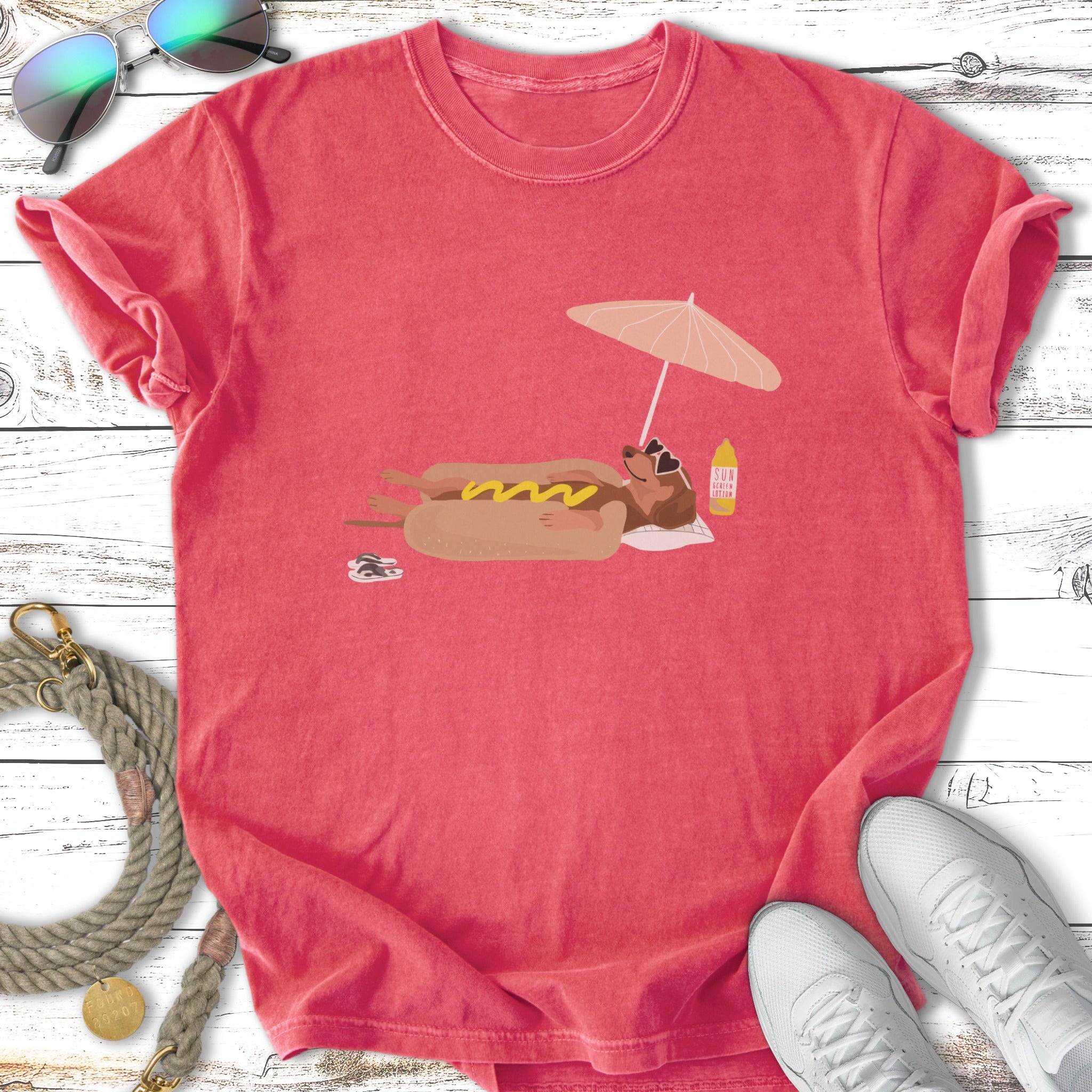 Cartoon hot dog with sunglasses relaxes under an umbrella on a beach.