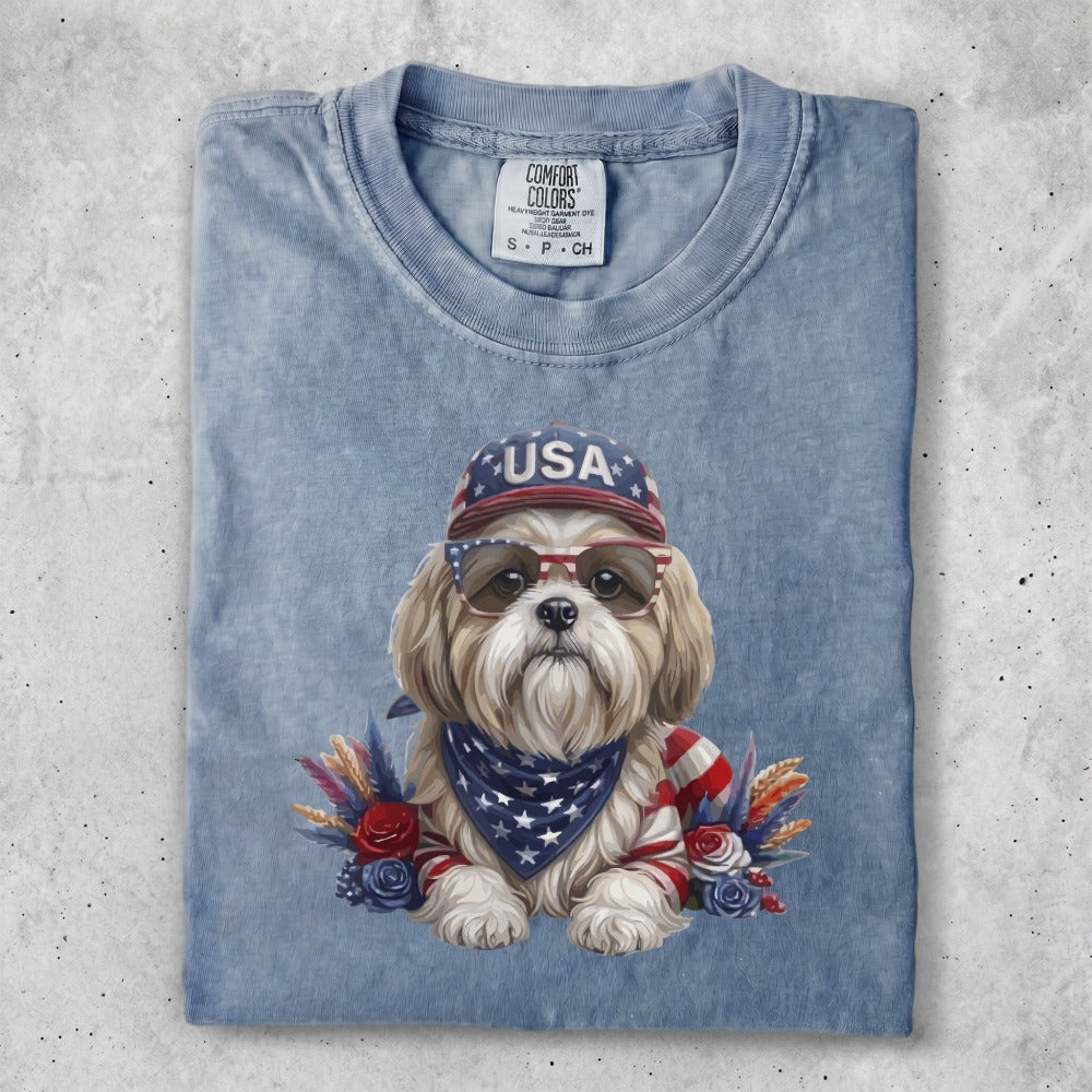 Dog wearing sunglasses and a USA bandana, with patriotic decorations.