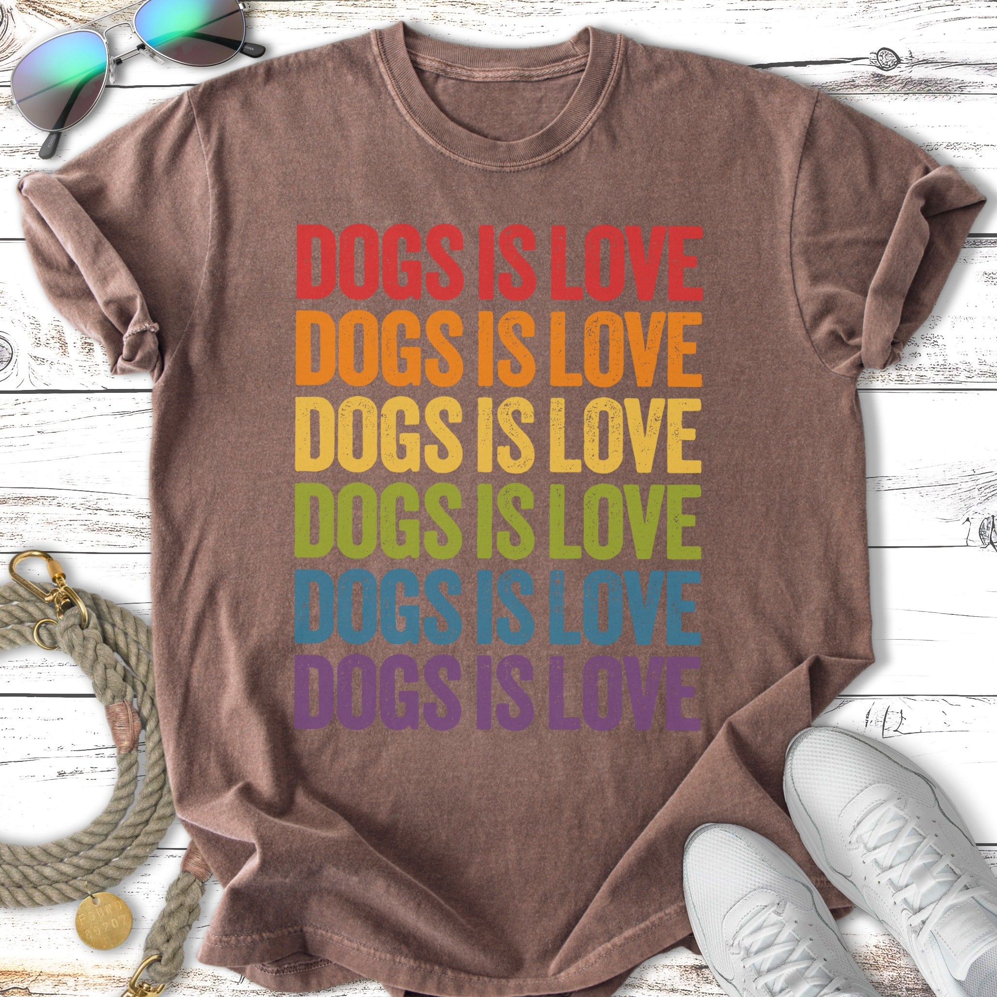 T-shirt with "DOGS IS LOVE" in rainbow colors on a vintage-wash background.