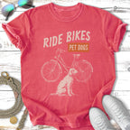 Coral t-shirt with distressed graphic of a bicycle and a dog, text reads "RIDE BIKES PET DOGS".
