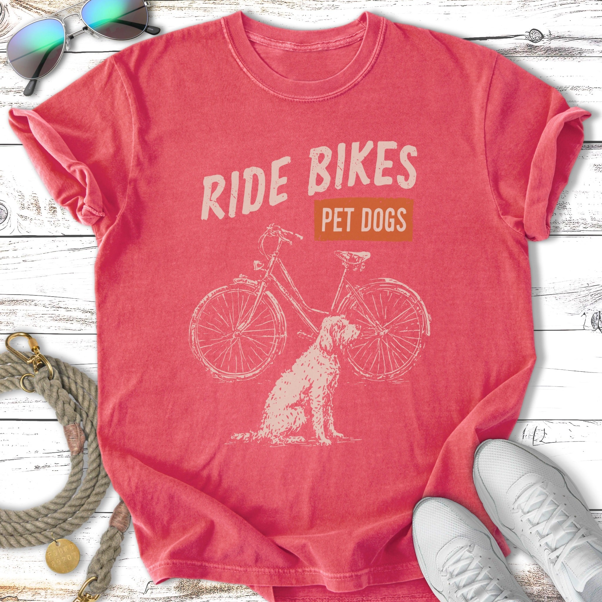 Coral t-shirt with distressed graphic of a bicycle and a dog, text reads "RIDE BIKES PET DOGS".