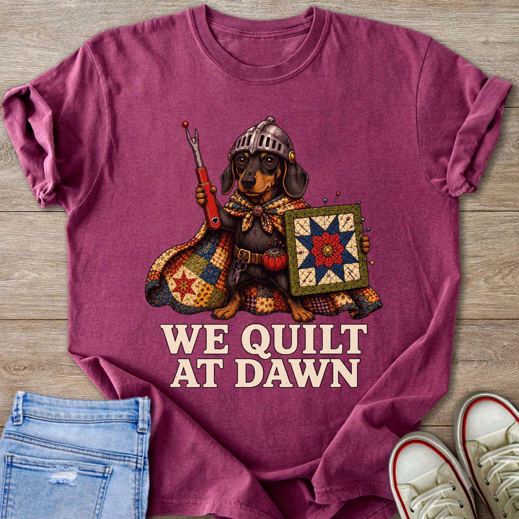 Shirt with a dachshund dressed as a knight, holding a seam ripper and quilt, text "We Quilt At Dawn".