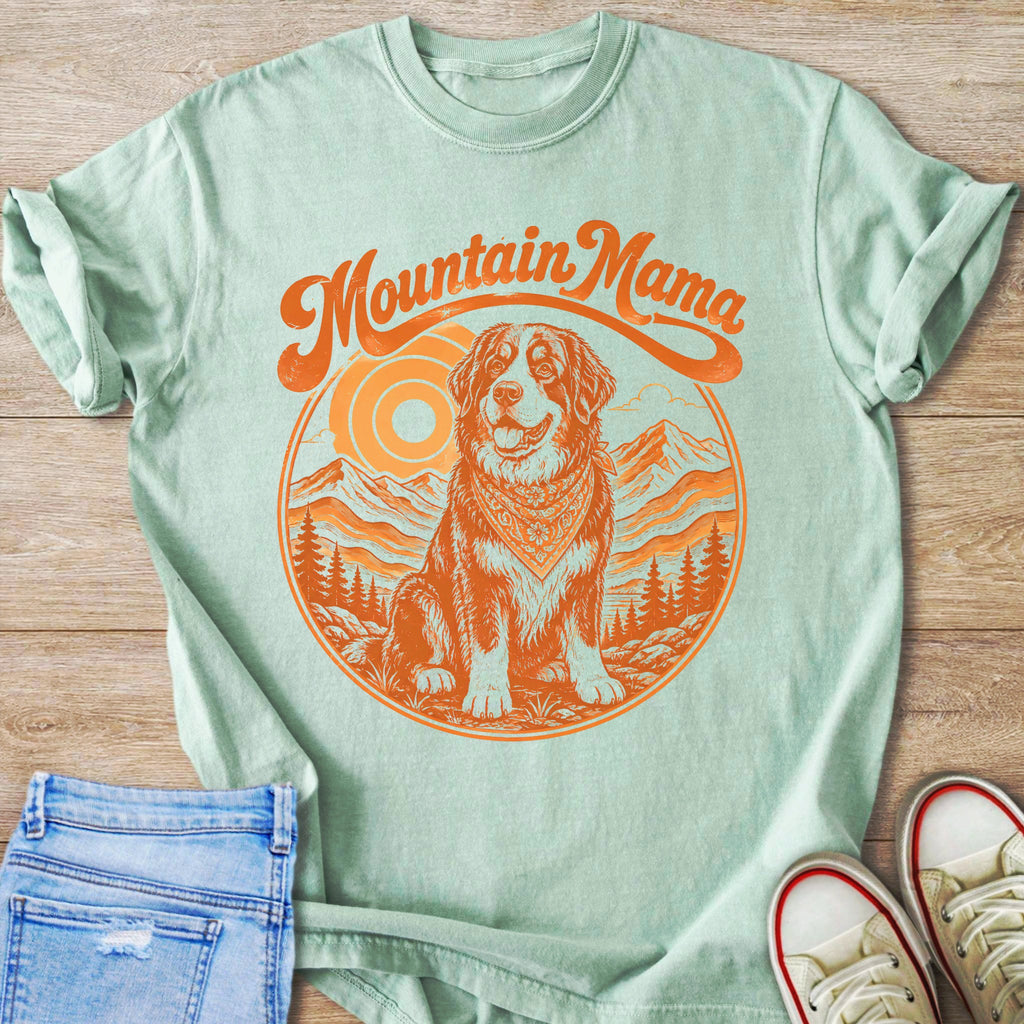Mint green t-shirt with "Mountain Mama" text and dog in mountain scenery graphic.