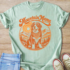 Mint green t-shirt with "Mountain Mama" text and dog in mountain scenery graphic.