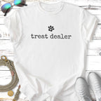 White t-shirt with "treat dealer" and paw print in black text.