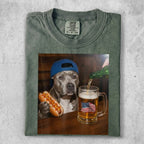 Pit bull wearing a blue cap holds a hot dog next to a beer mug with an American flag.