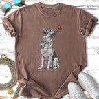 German Shepherd dog looking up at a butterfly on a brown t-shirt.