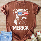 Dog in sunglasses with the American flag design and text 'MERICA on a maroon t-shirt.