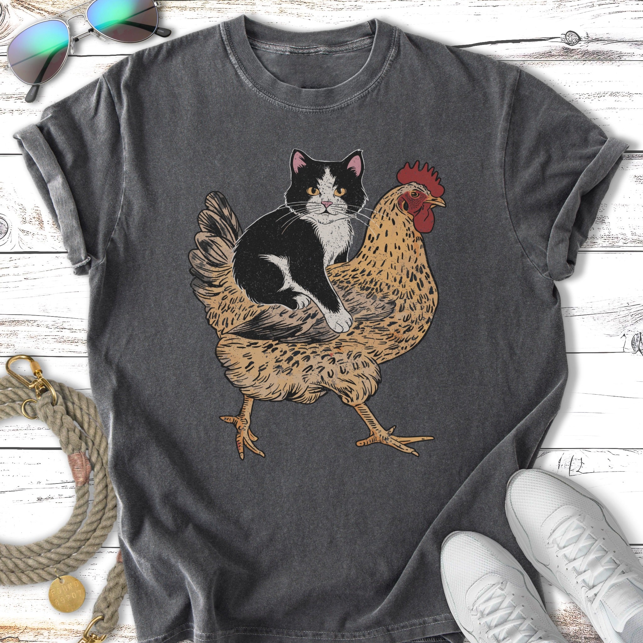 Black and white cat riding a chicken on a dark grey t-shirt.