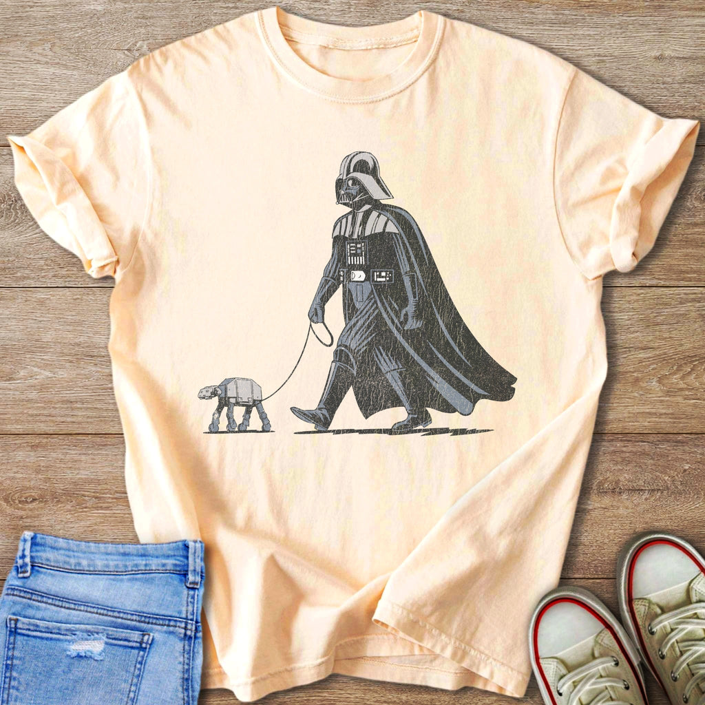 Darth Vader walking an AT-ST walker on a leash, vintage graphic on a peach t-shirt.