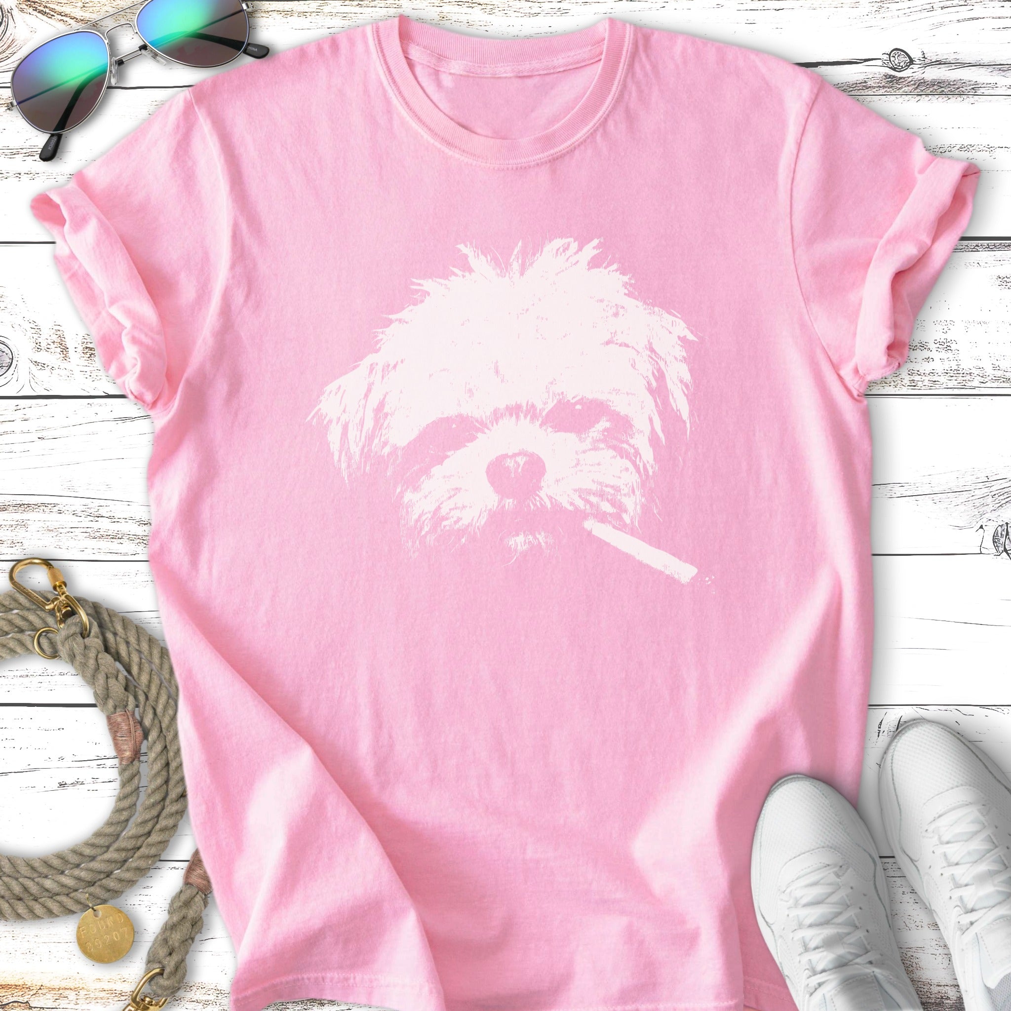 White Shih Tzu dog wearing a cigarette on a pink t-shirt.