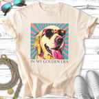 Golden retriever wearing sunglasses on a peach shirt with text "IN MY GOLDEN ERA".