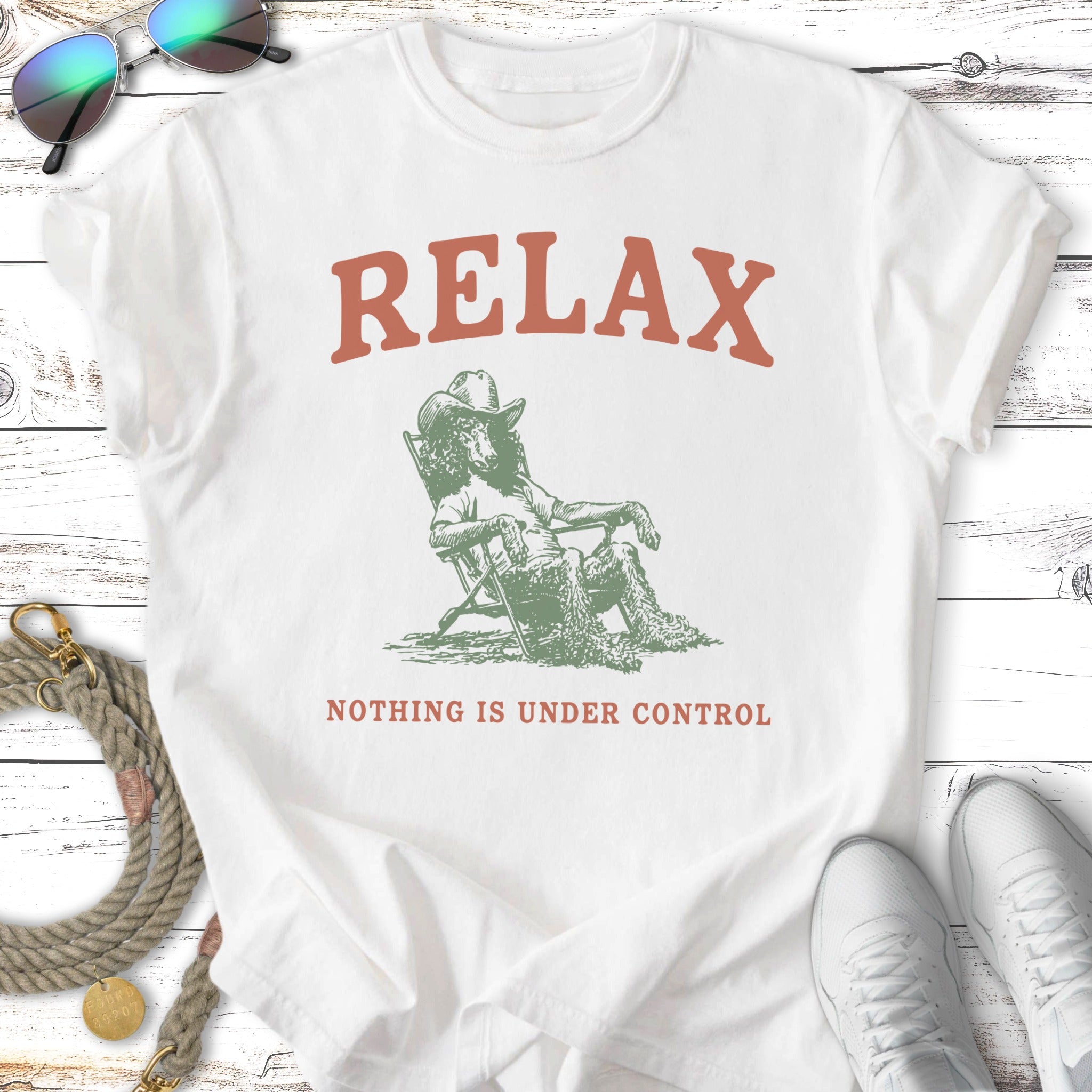 White t-shirt with "RELAX NOTHING IS UNDER CONTROL" text and illustration.
