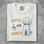 White t-shirt with "COFFEE AND DOODLES" text and a doodle dog illustration.