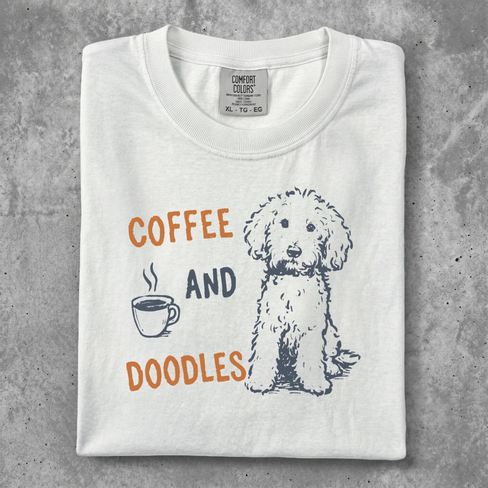 White t-shirt with "COFFEE AND DOODLES" text and a doodle dog illustration.