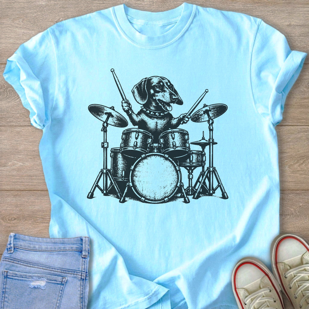 Dachshund playing a drum set in black ink on a light blue t-shirt.