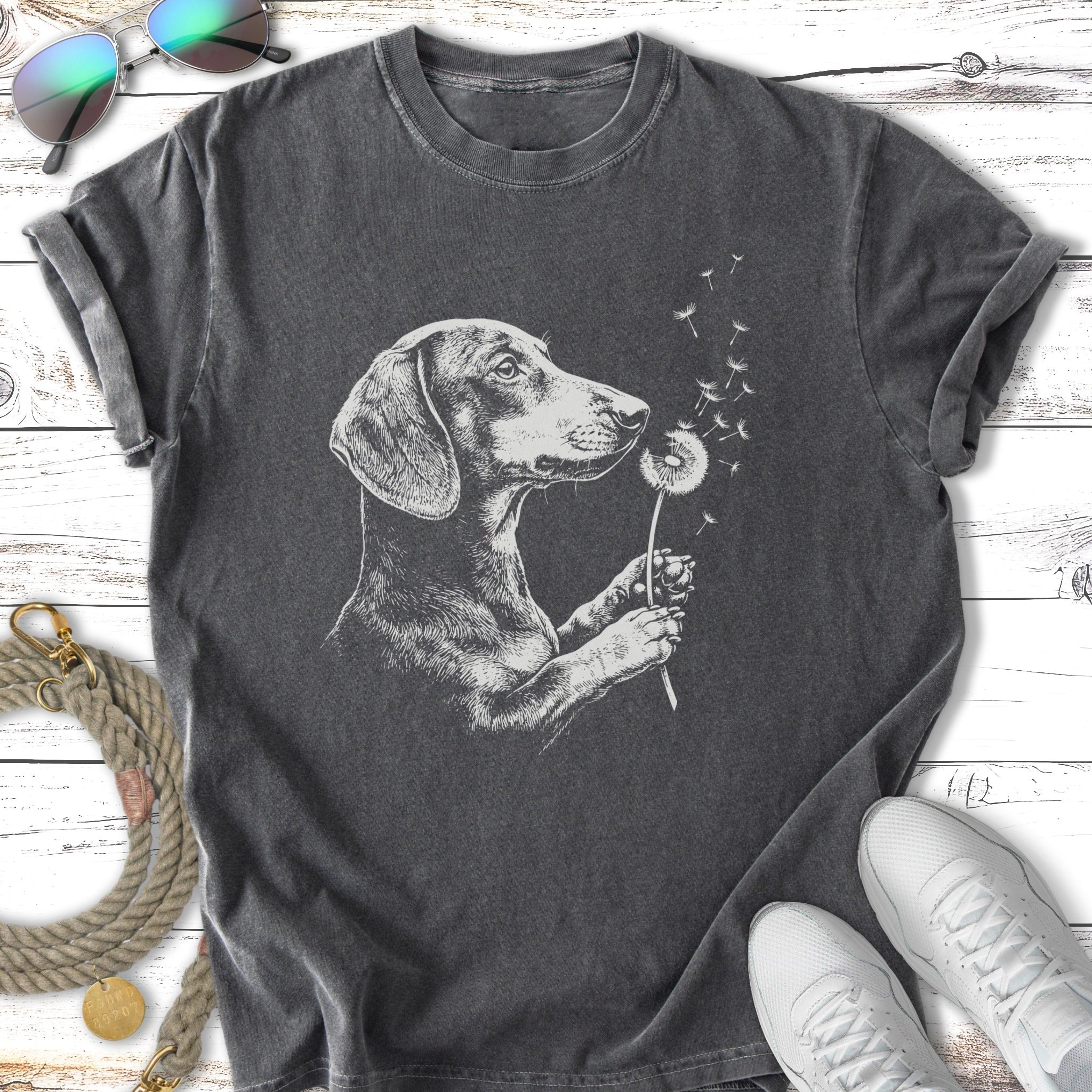 Dachshund holding a dandelion with blowing seeds, charcoal t-shirt.