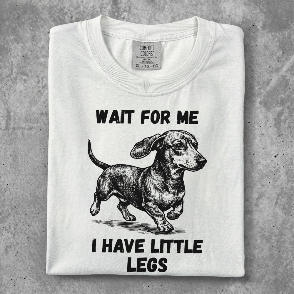White t-shirt with dachshund graphic and text "WAIT FOR ME I HAVE LITTLE LEGS".