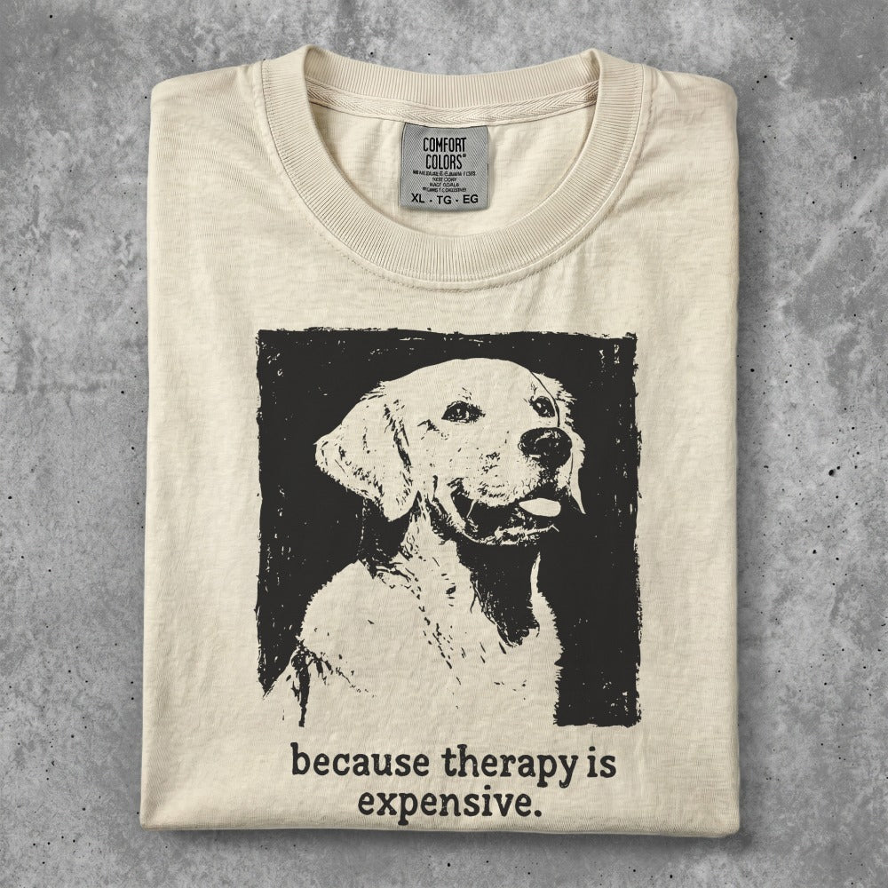 Cream t-shirt with black graphic of a golden retriever and text "because therapy is expensive."