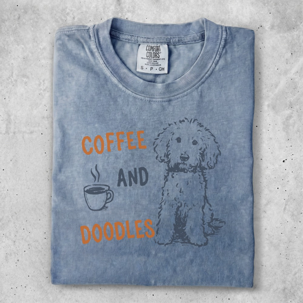 Blue Comfort Colors t-shirt with "COFFEE AND DOODLES" text and a dog illustration.