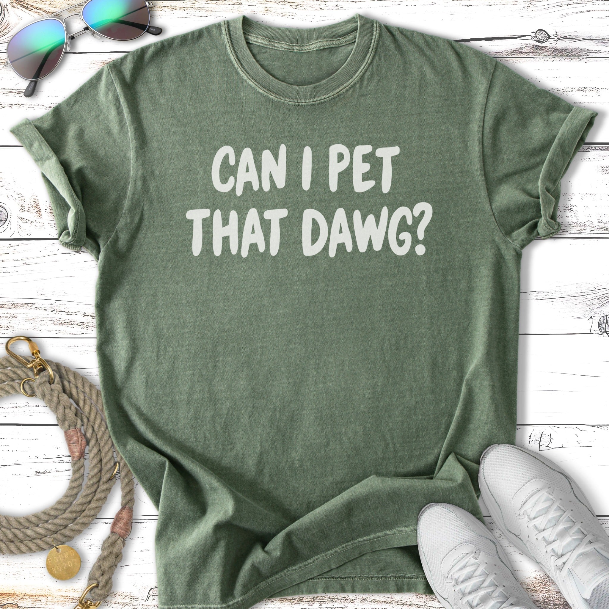 Green t-shirt with "CAN I PET THAT DAWG?" text, sunglasses, leash, and sneakers.