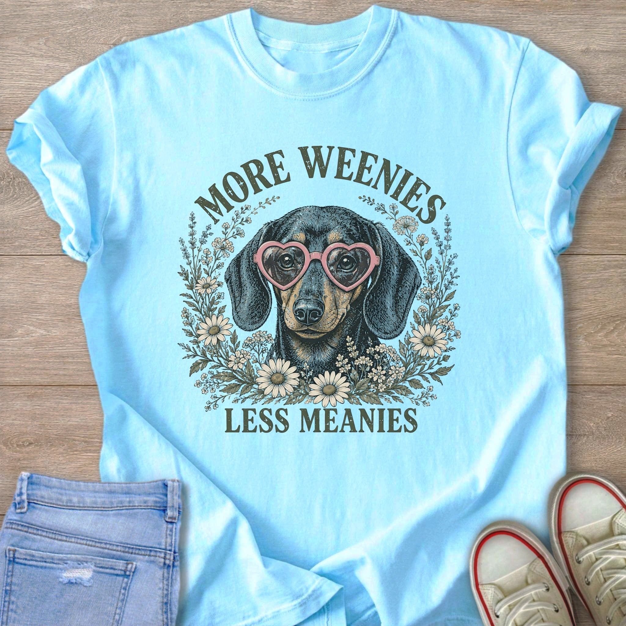 Light blue t-shirt with a dachshund wearing heart sunglasses and text saying "More Weenies Less Meanies".