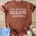 Brown t-shirt with white text reading "this dog thing ESCALATED quickly" and a paw print.