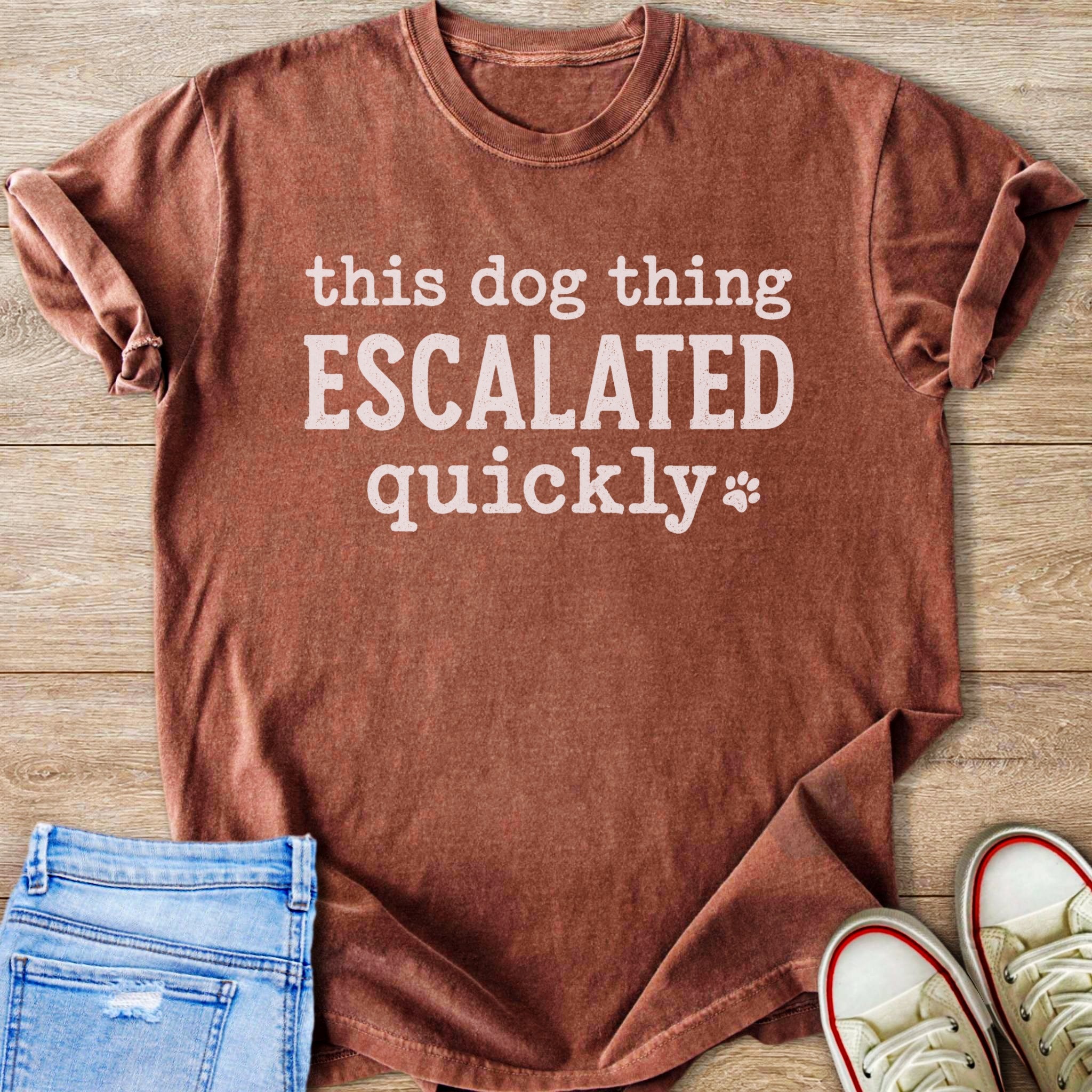 Brown t-shirt with white text reading "this dog thing ESCALATED quickly" and a paw print.