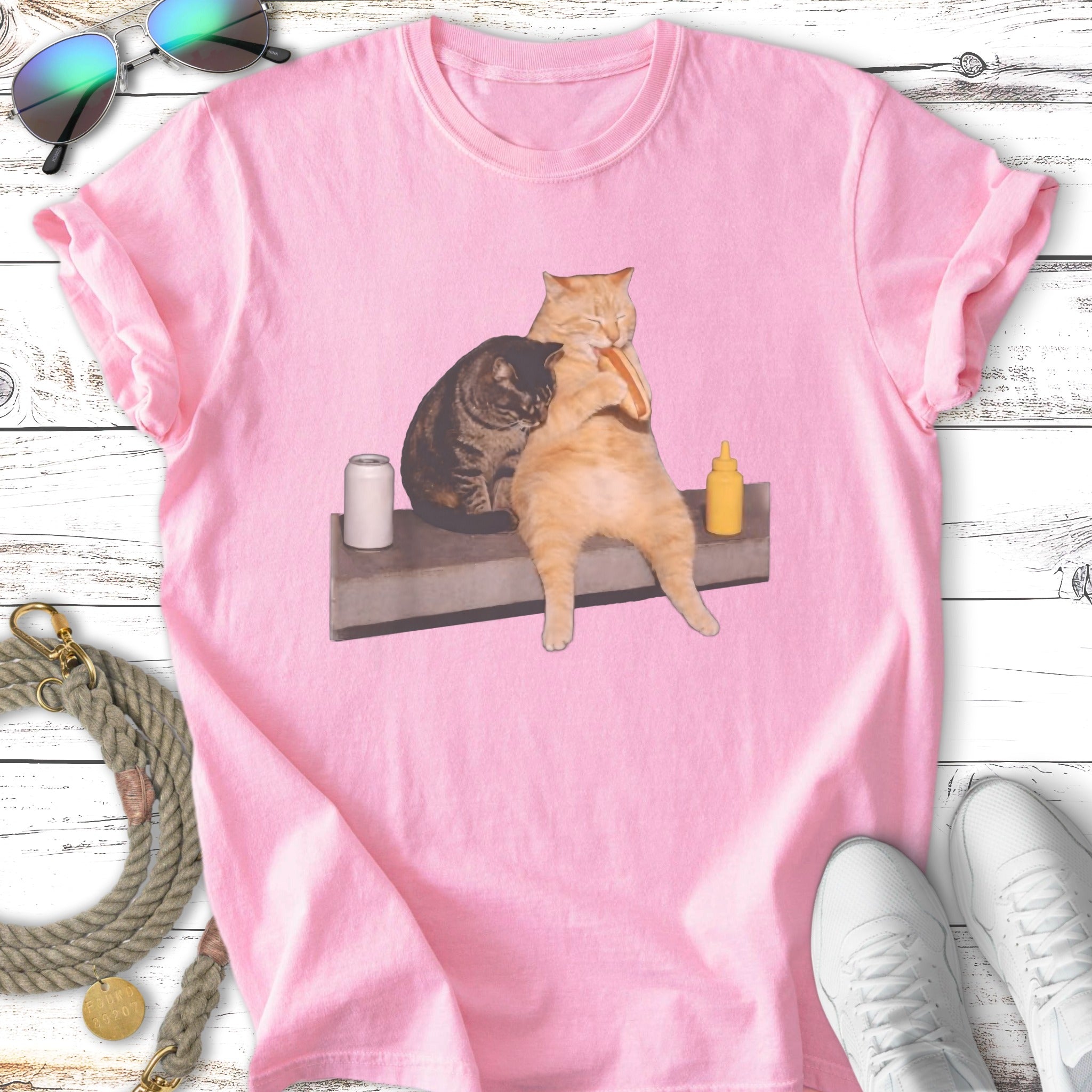 Two cats hug, one holding a hot dog, on a t-shirt.