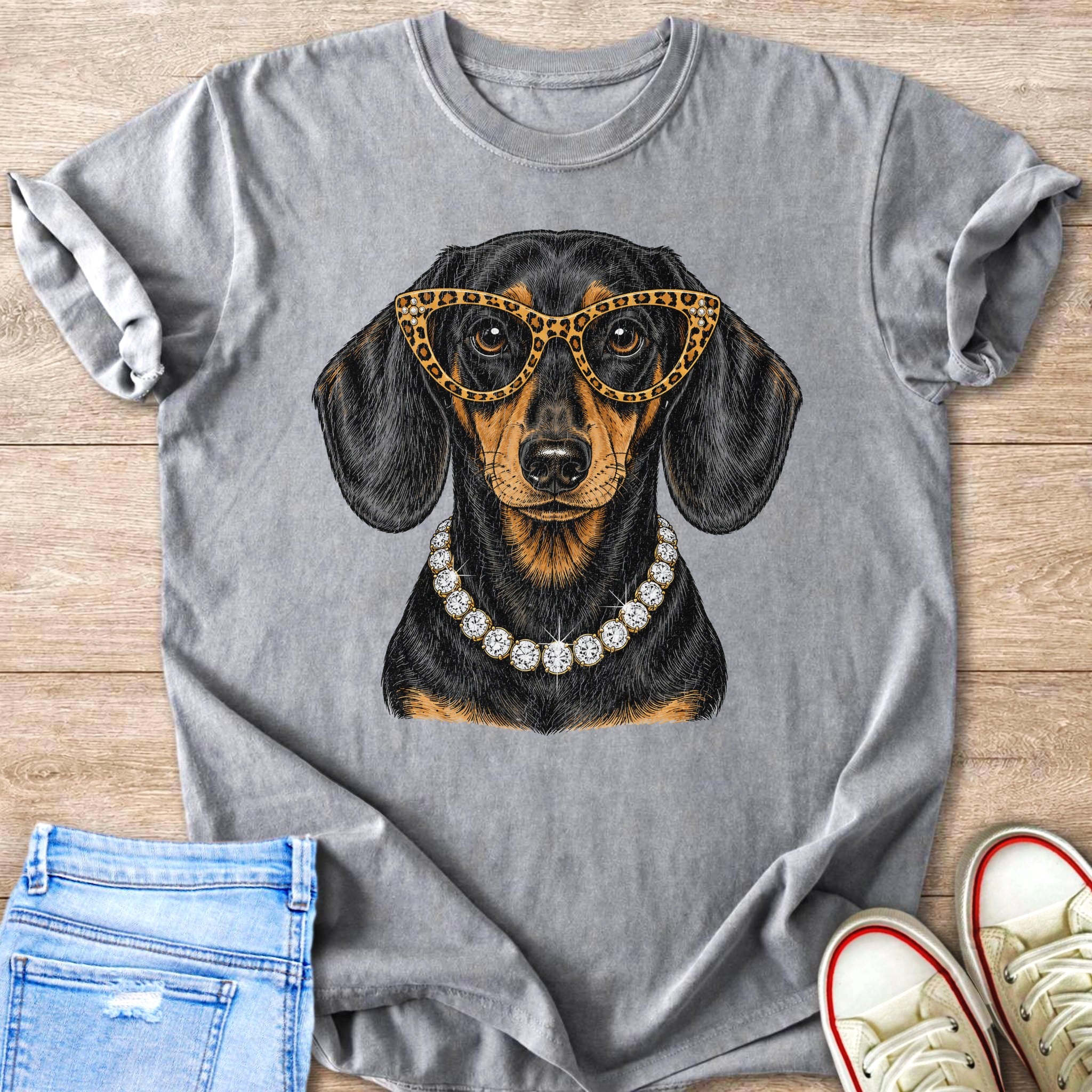 Dachshund wearing glasses and pearl necklace on grey t-shirt with jeans and sneakers.