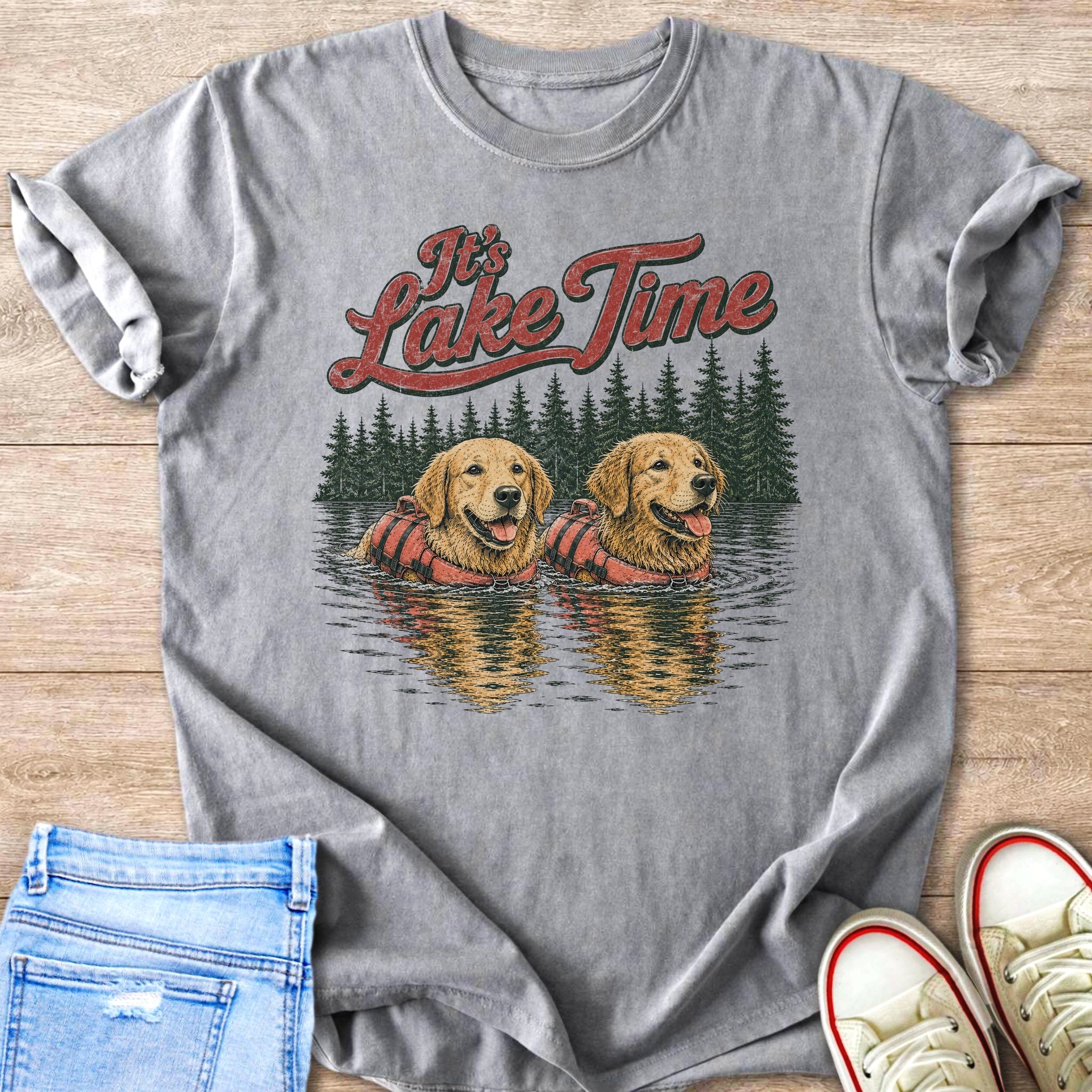 Two golden retrievers in life vests swim in a lake with pine trees.