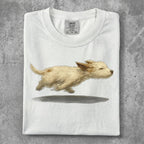 White t-shirt featuring a painted illustration of a running golden puppy.