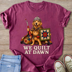Golden retriever knight holding quilt and seam ripper, text reads "WE QUILT AT DAWN".